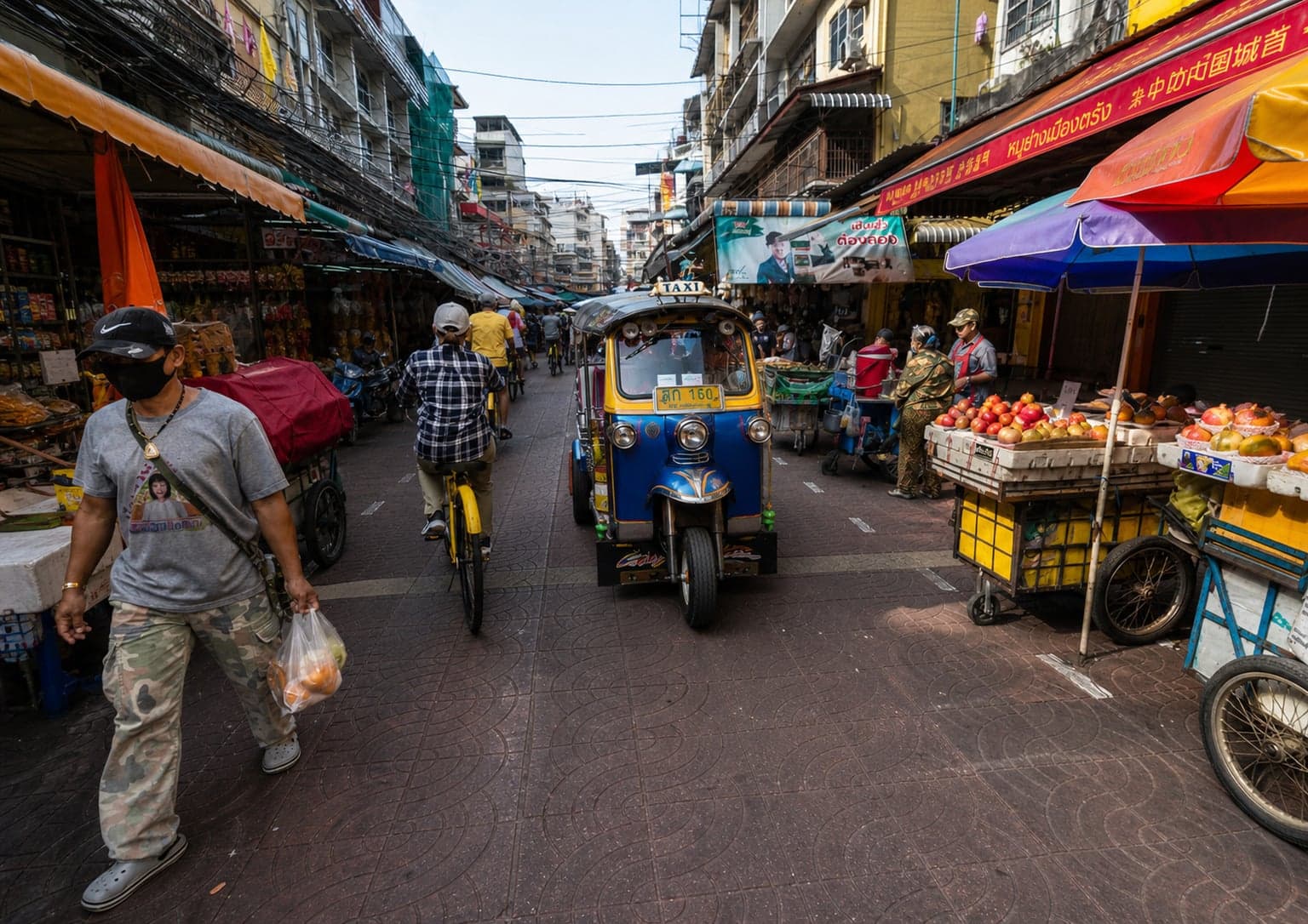 Tuk-tuk passing a Chinatown market street on the Bangkok walking tour